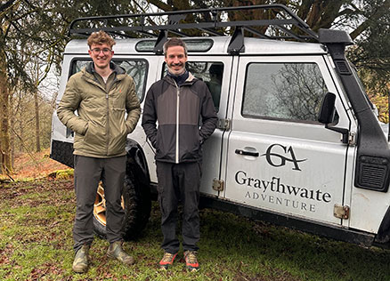 Cumbria Tourism staff members Dan and Ben posing with a Graythwaite Adventure Land Rover